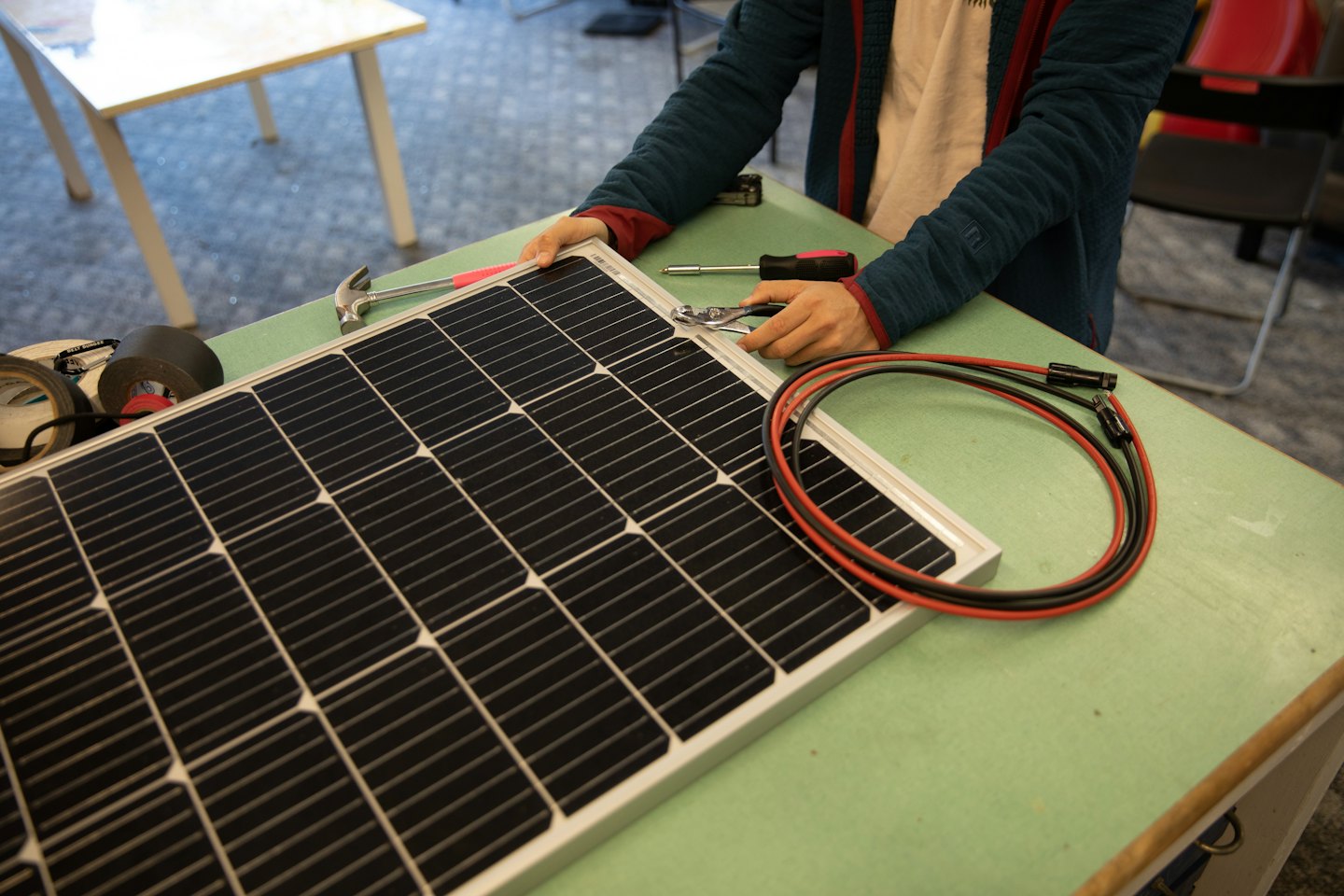 Pracovník montuje solárny panel kliešťami na pracovnom stole.